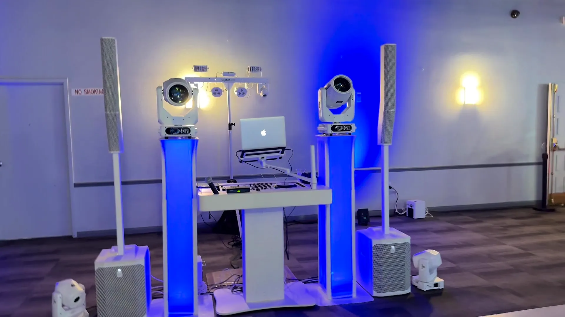 White DJ booth with blue uplit totems and moving-head lights ready for a wedding reception in a Cape Coral ballroom