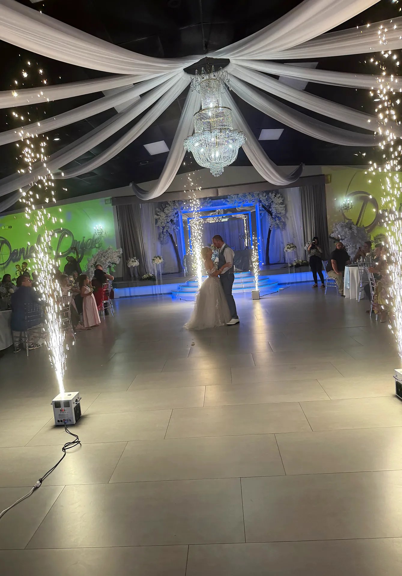 Bride and groom share a first dance framed by cold spark fountains and ceiling draping at a Cape Coral wedding