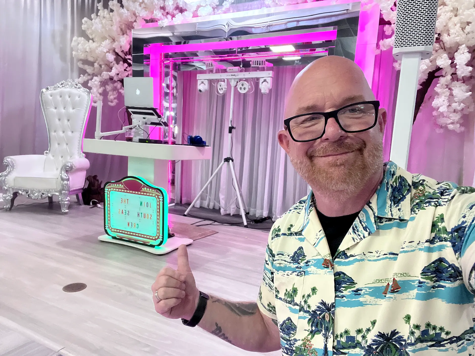 DJ Bigs, owner of Big Events Florida, gives a thumbs-up in front of his DJ booth and pink-lit stage at a Cape Coral event