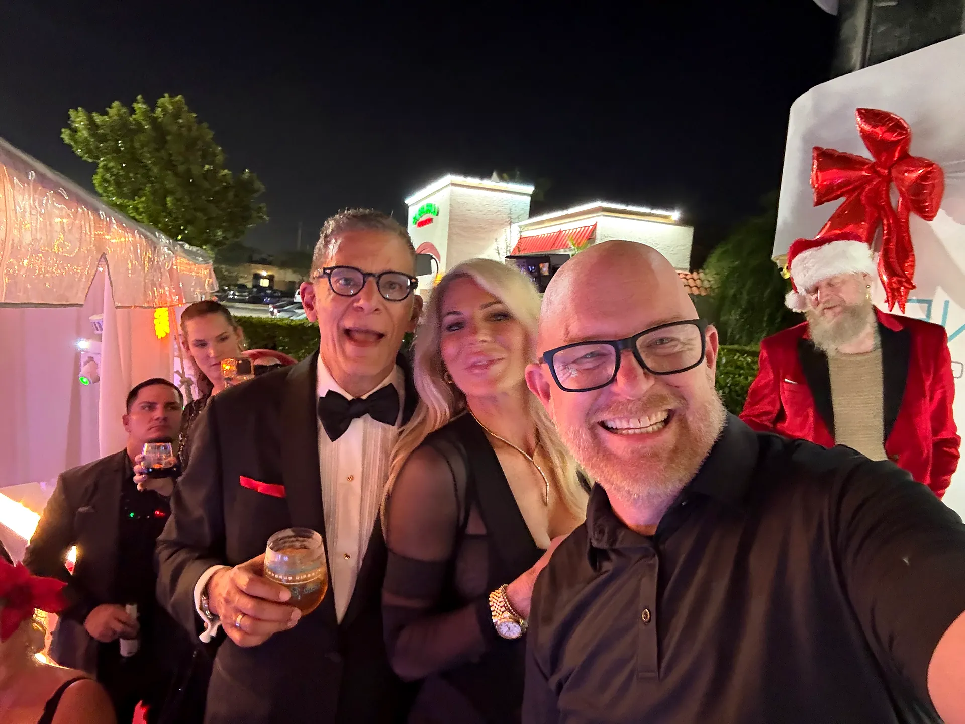 DJ Bigs takes a selfie with dressed-up guests and Santa at a Fort Myers holiday party
