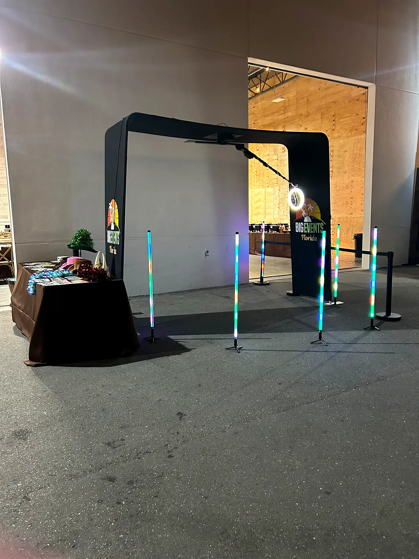 Big Events LED arch photo booth backdrop with light-up stanchions and a prop table set up for an event in Alva