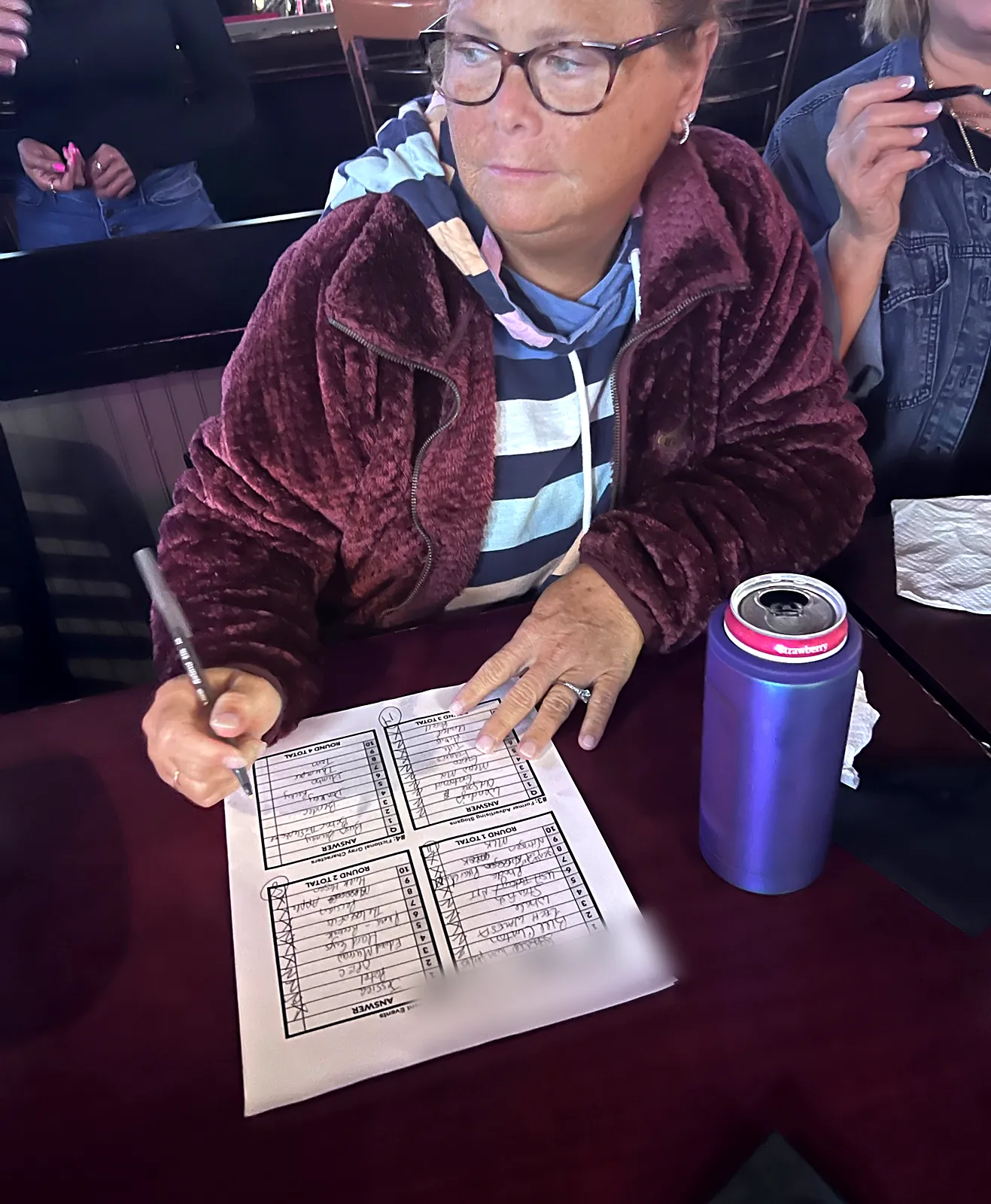 A trivia player fills in a round-by-round answer sheet with a pen at a Southwest Florida bar trivia night